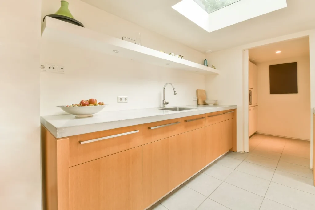 Cocina lineal con muebles de madera clara y encimera blanca